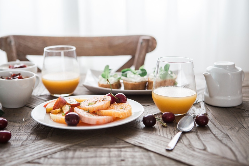 Auf dem Bild sieht man einen gedeckten Frühstückstisch mit Obst, Broten und Getränken.