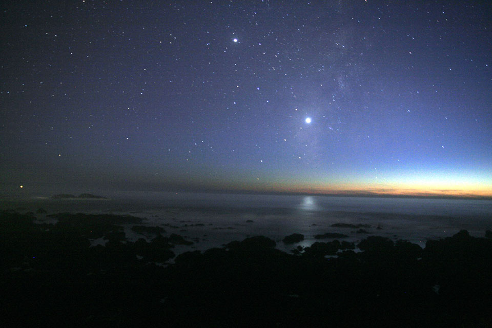 Foto des Sternenhimmels über einer Meeresküste mit der hell leuchtenden Venus