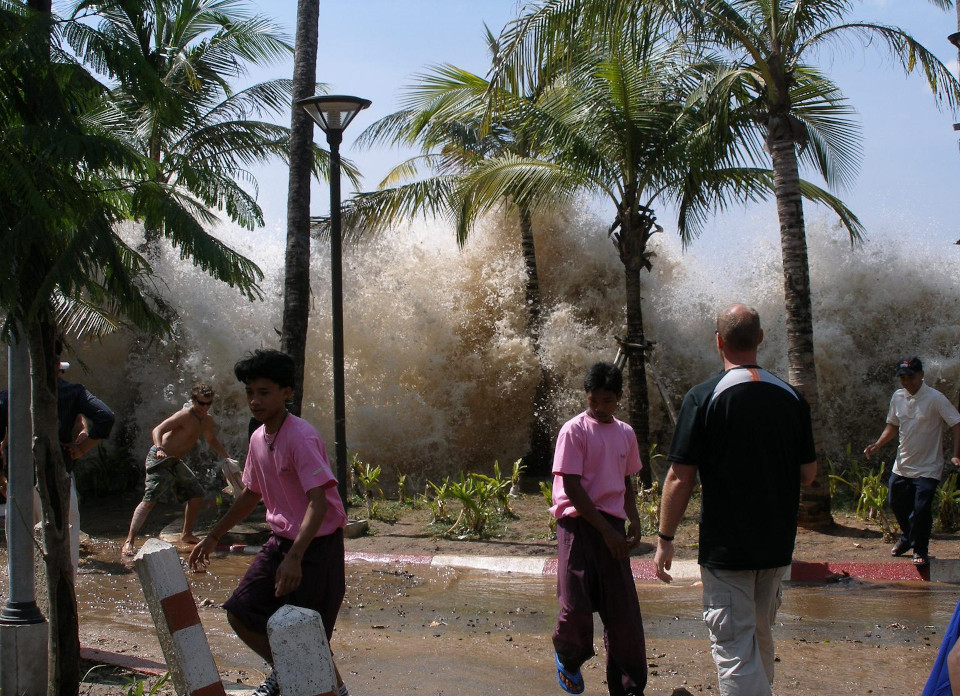 Ein Bild einer kommenden Flutwelle zwischen Palmen an der Küste Thailands bei Ao Nang - Menschen flüchten