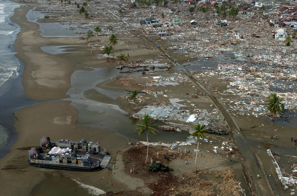 Flugzeugaufnahme der Stadt Meulaboh, auf der Insel Sumatra in Indonesia, nach einer Flutwelle. Die Küste ist zerstört, mit wenigen Palmen die noch stehen, umgeben von Schlamm und Gebäudetrümmern.