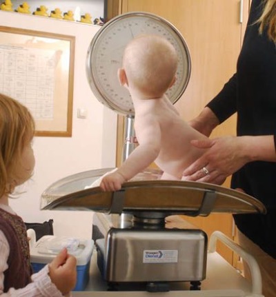 Ein Baby sitzt auf einer Waage