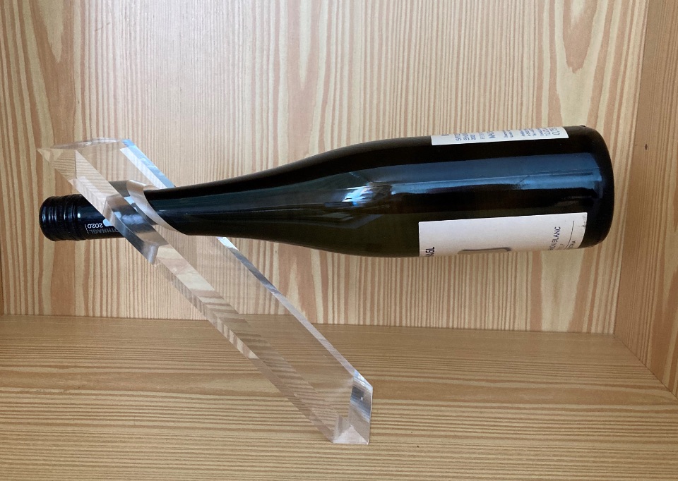 Eine Weinflasche steckt mit dem Hals in einer freistehenden Kunststoffvorrichtung und scheint zu schweben.
