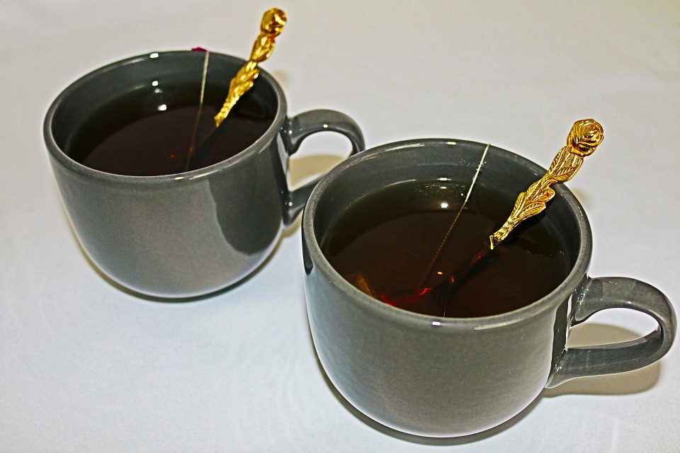Eine Tasse heißer Tee mit einem Metalllöffel und eine Tasse mit einem Plastiklöffel drinnen