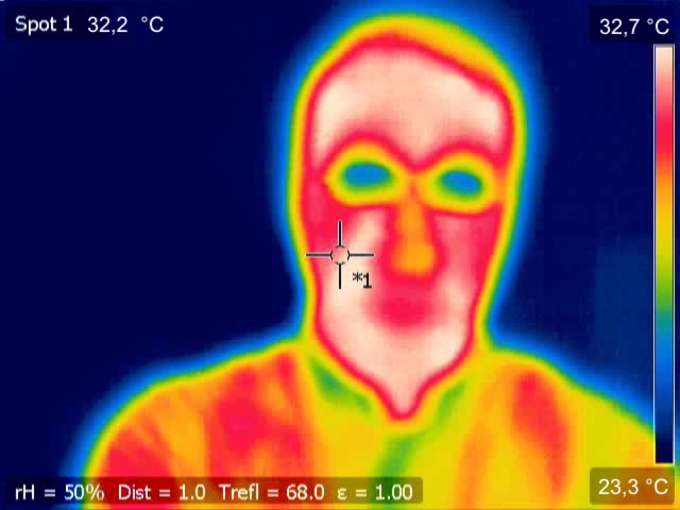Wärmebild einer Person mit Brille. Die Nase strahlt etwas weniger, die Brille bei weitem weniger Wärme ab als das restliche Gesicht.